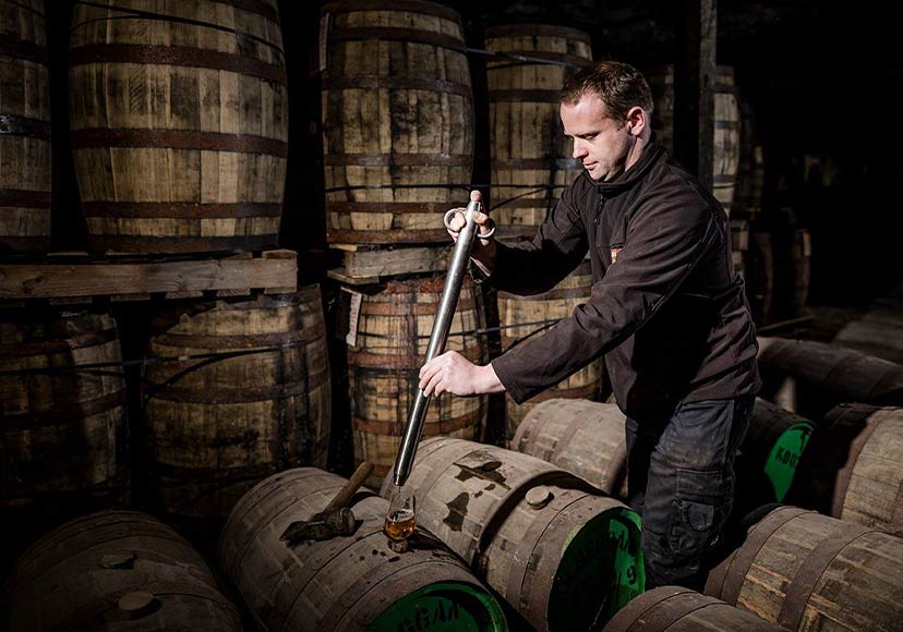 Worker taking whiskey samples.